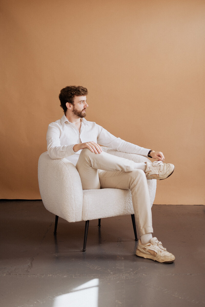 Tom Wyatt sitting in a cream armchair