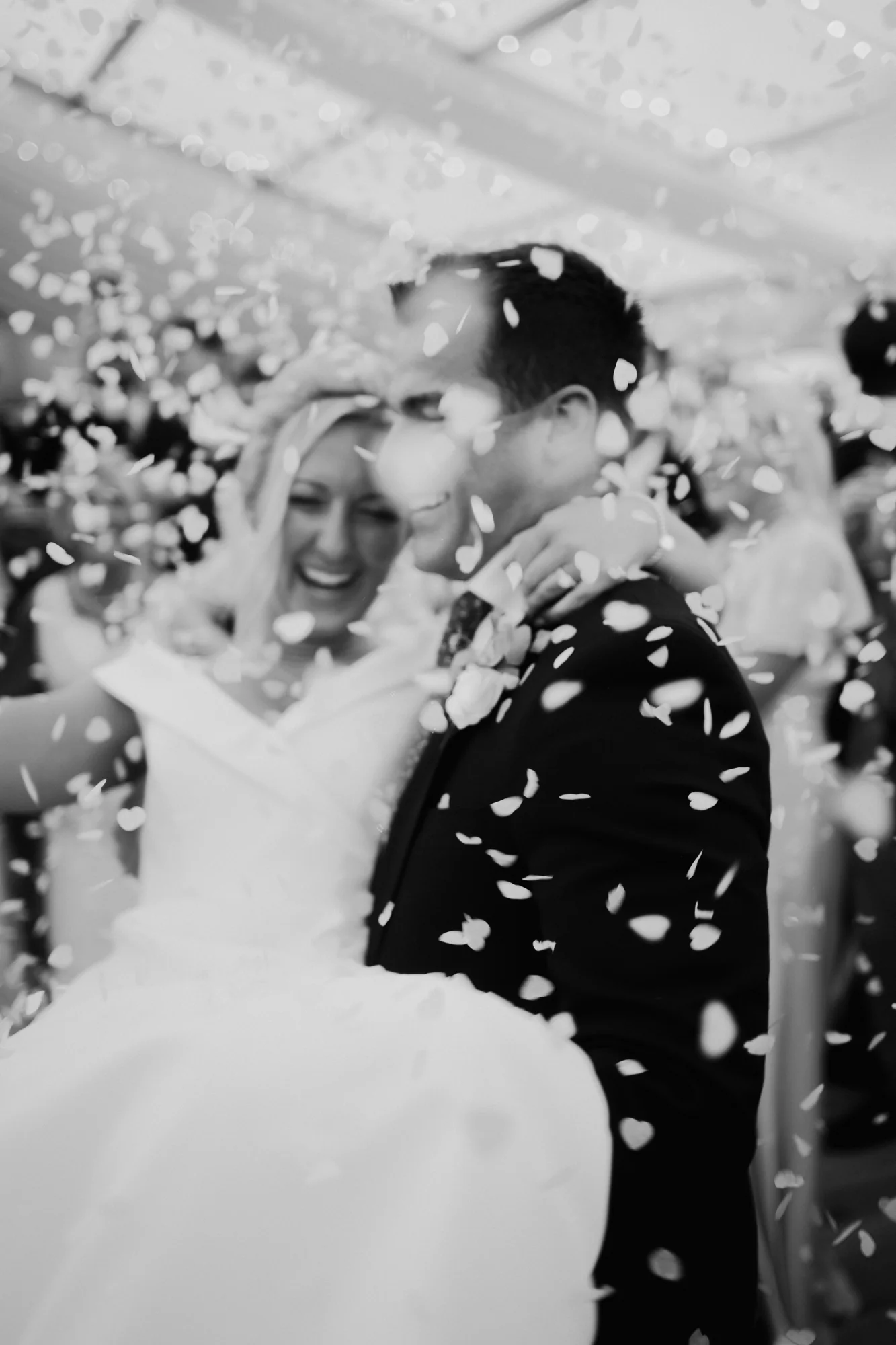 Black-and-white photograph of a couple dancing beneath falling confetti