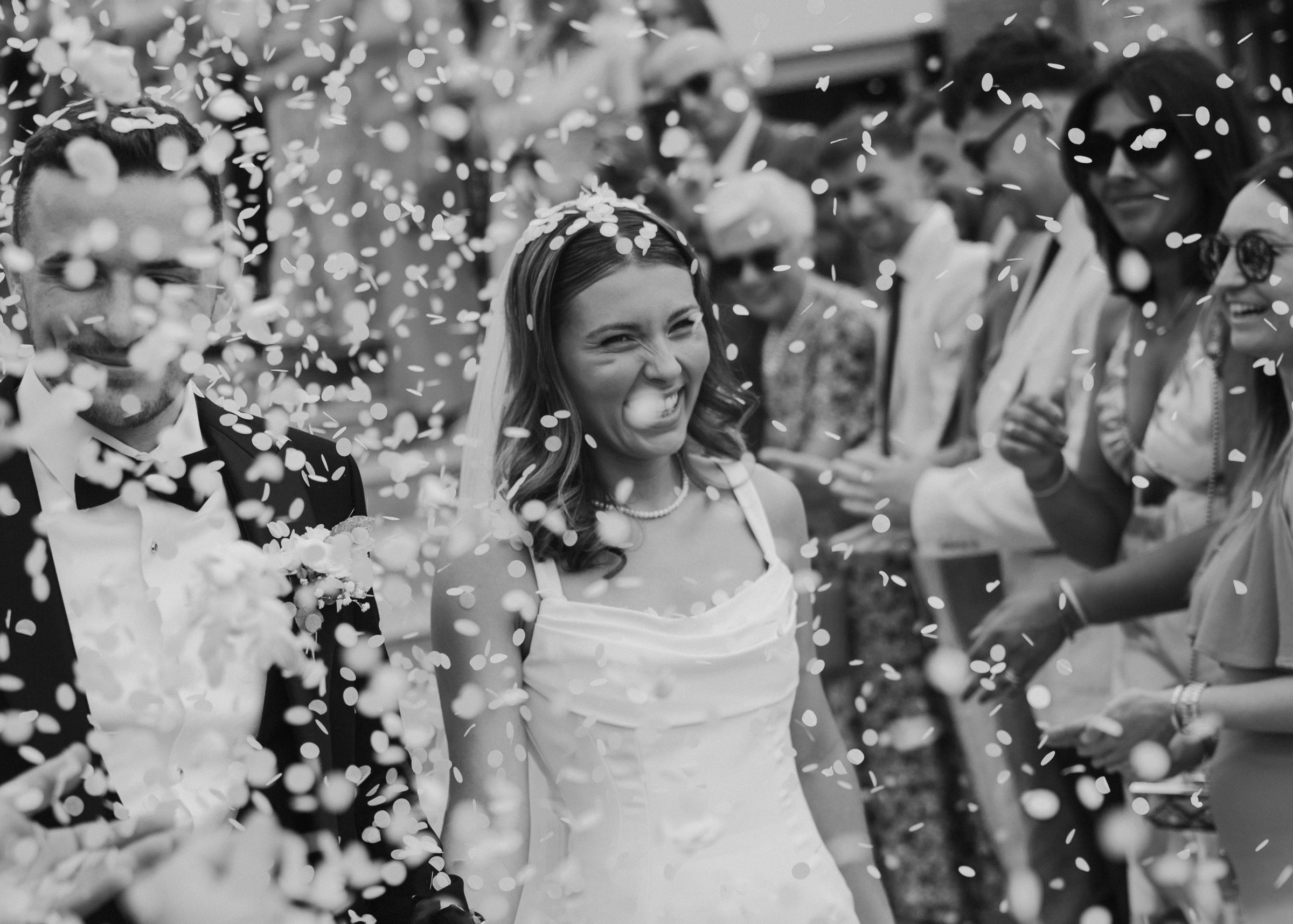 A newly married couple laughing as confetti falls around them