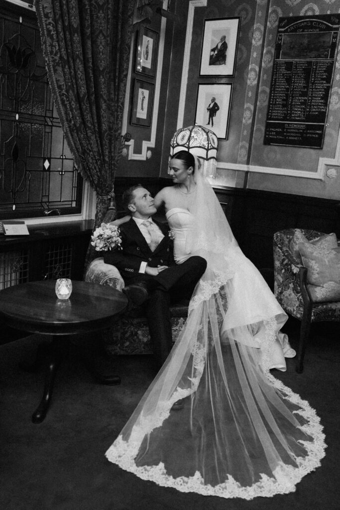 Black-and-white portrait of the couple with the bride's lace-edged veil spread out