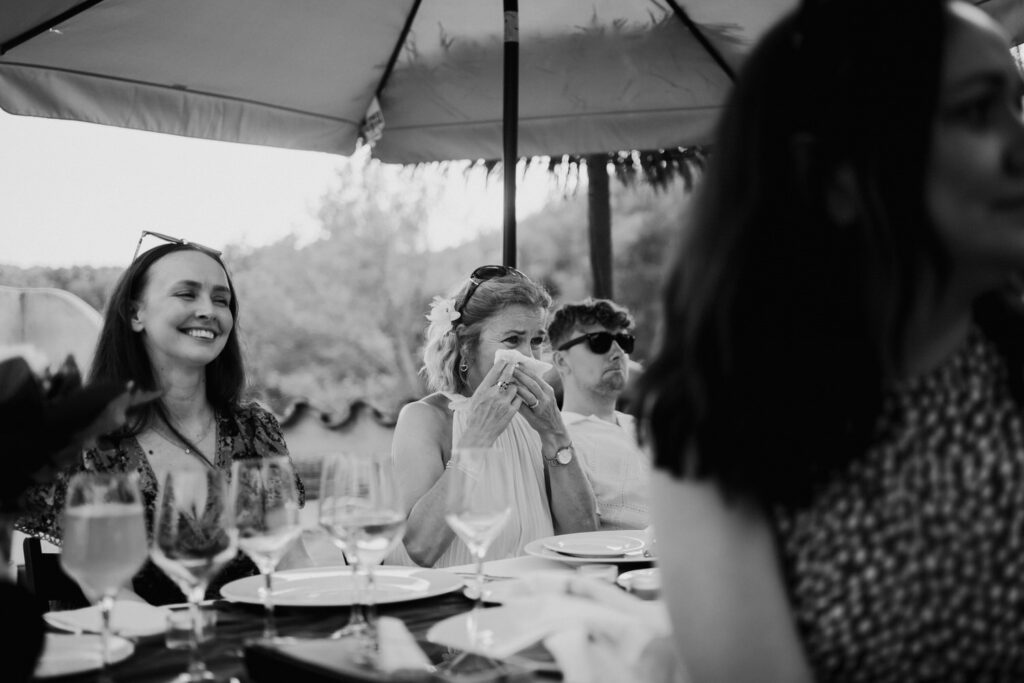 Black-and-white photograph of guests laughing at the reception table