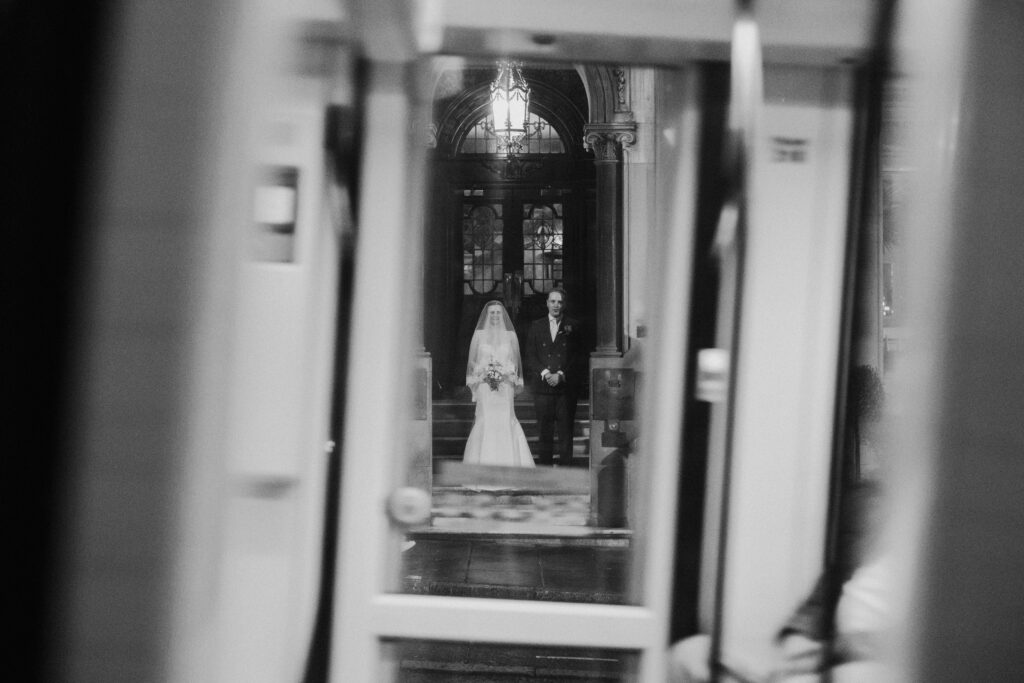 Black-and-white portrait of a bride seen through a series of doorways
