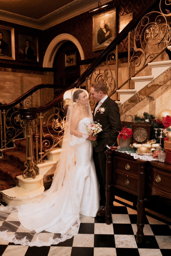 Bride and groom standing beside Cosy Club's ornate staircase