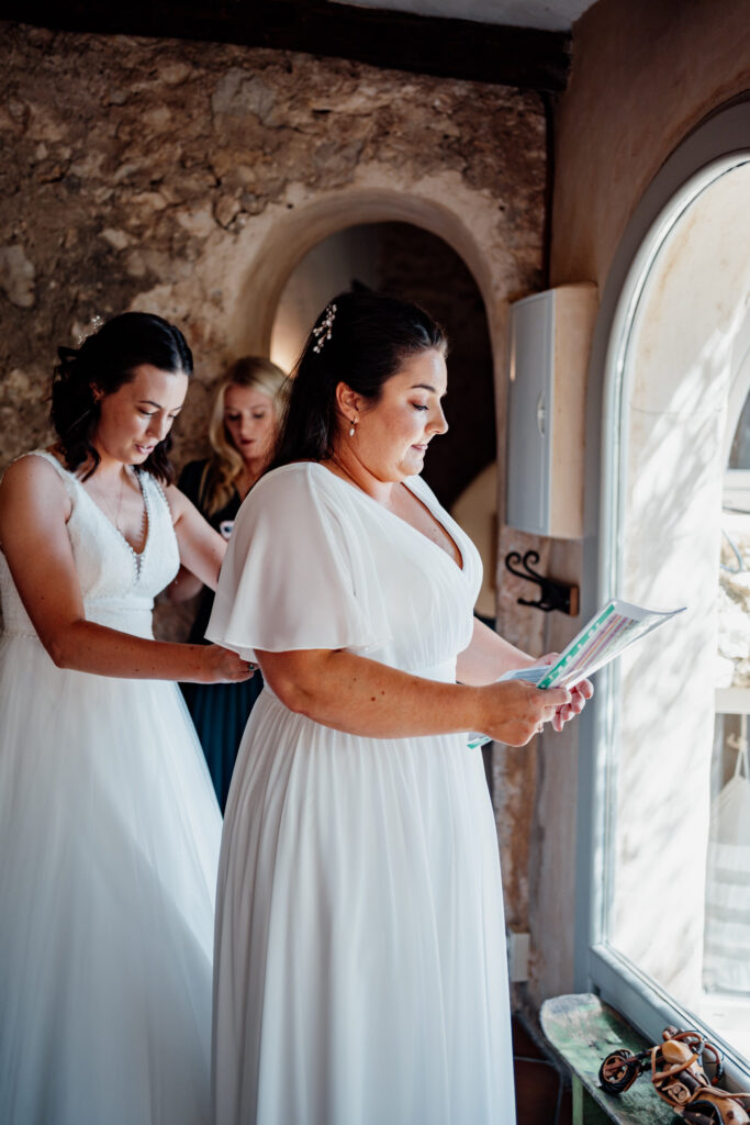 Bride reading a card while her partner stands behind her