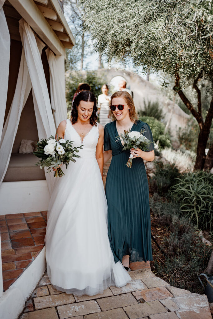 Bride walking arm in arm with a guest in a green dress
