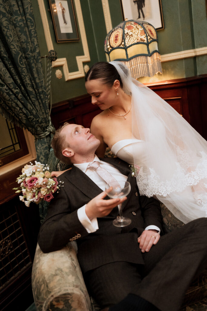 Bride and groom sharing a kiss beside the armchair