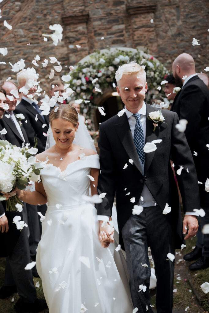 Newlyweds walking through confetti outside the church