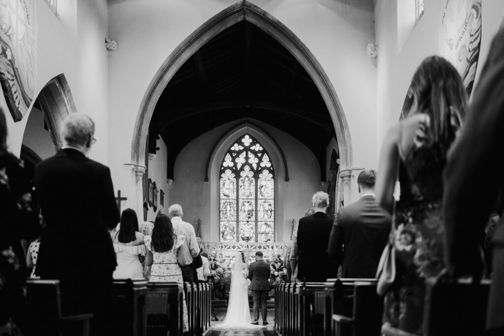 Black-and-white view down the church aisle during the ceremony