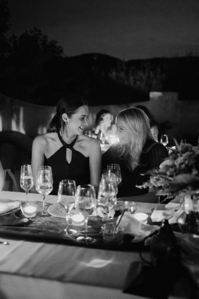 Black-and-white photograph of two guests sharing a kiss at dinner