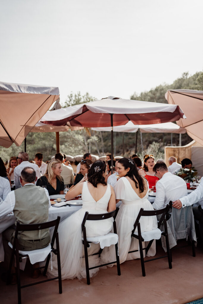 Guests seated beneath parasols at the outdoor wedding breakfast