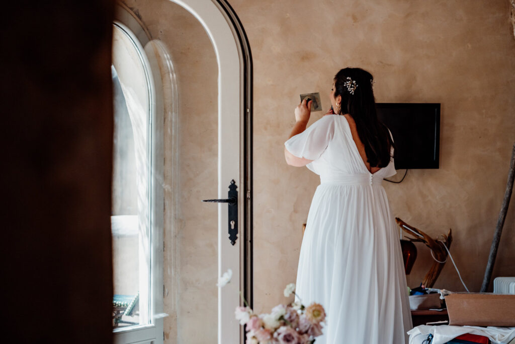 Bride standing beside an arched bedroom window