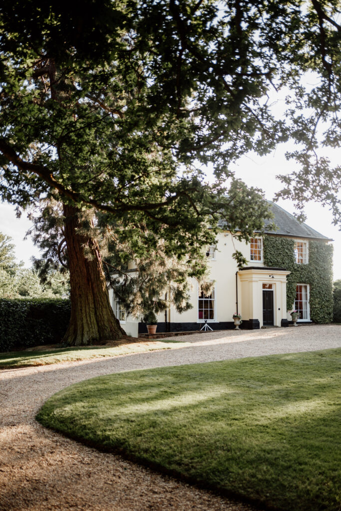 Country house and gravel driveway beneath a spreading tree