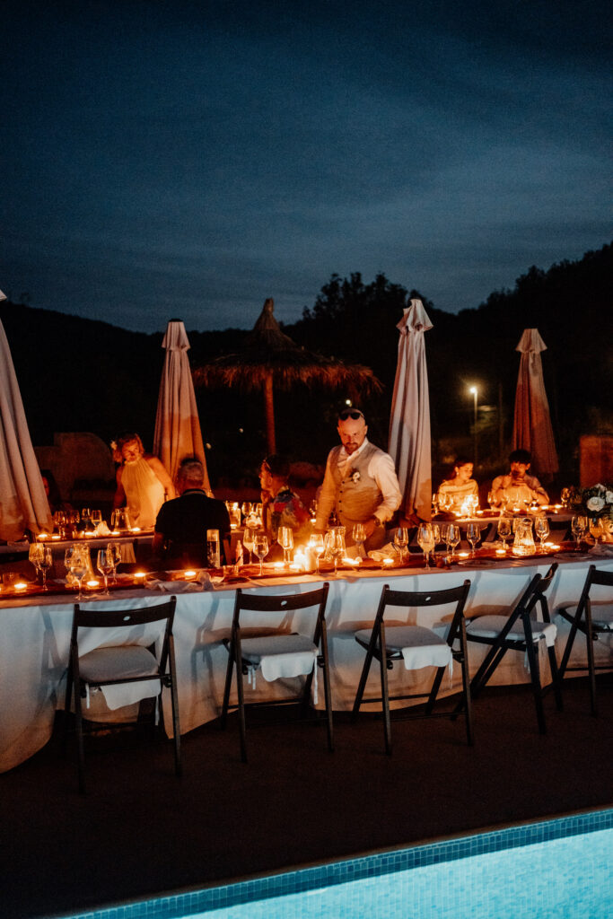 Candlelit reception table beside the pool after dark
