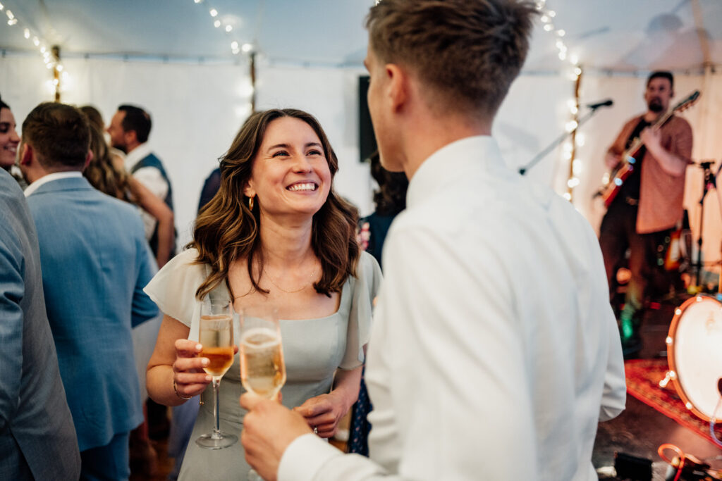 Wedding guests chatting with drinks beneath marquee lights