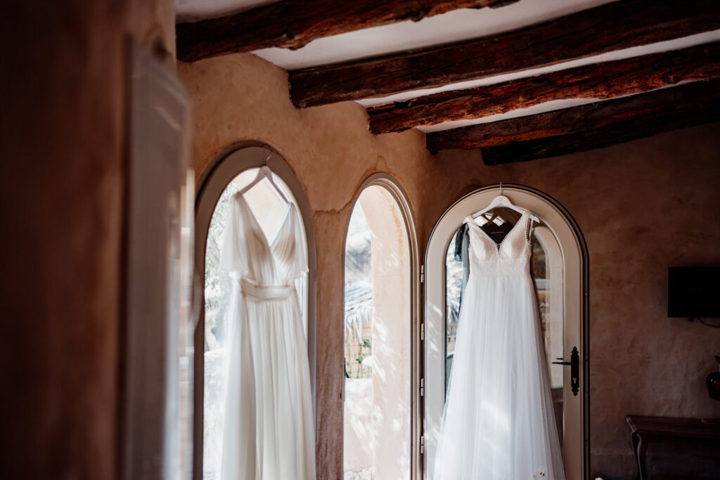 Wedding dress and arched windows beneath wooden ceiling beams