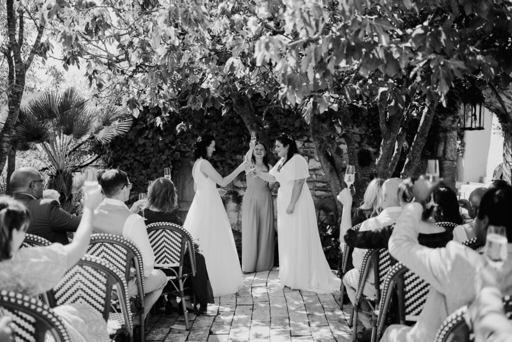 Black-and-white view of an outdoor wedding ceremony beneath a tree
