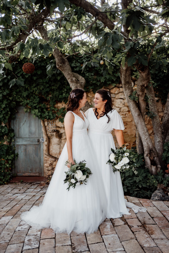 Two brides sharing a kiss beneath the ceremony tree