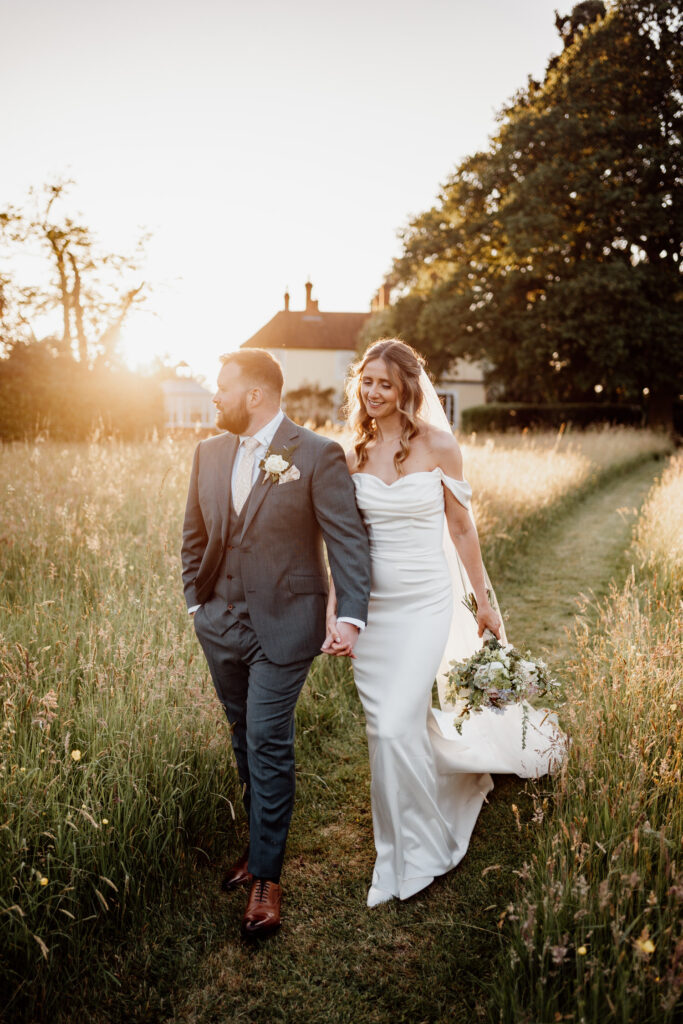 Bride carrying her bouquet as she walks beside the groom at sunset