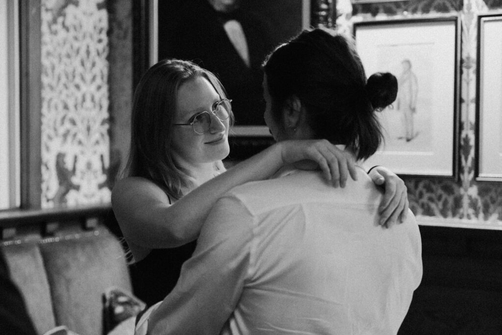 Black-and-white photograph of two guests embracing at the reception