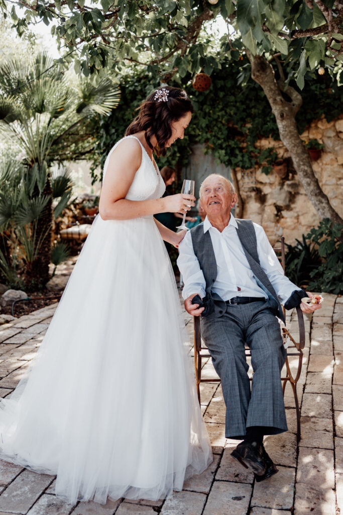 Bride chatting with an older guest seated on the garden terrace