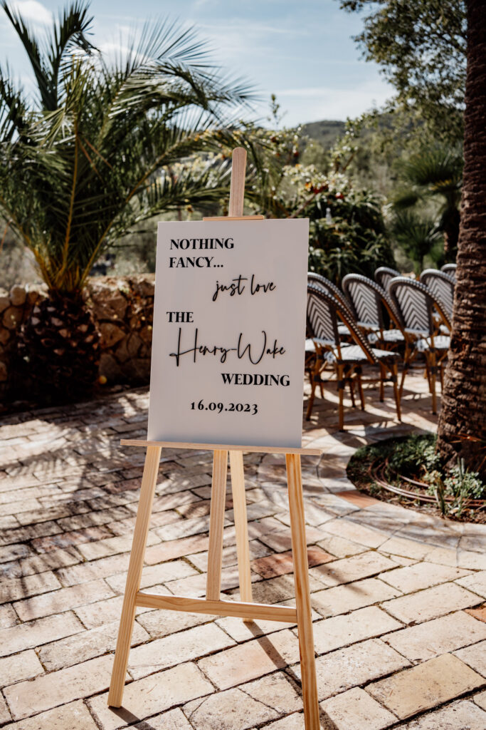 Wedding welcome sign on an easel beside the outdoor ceremony chairs