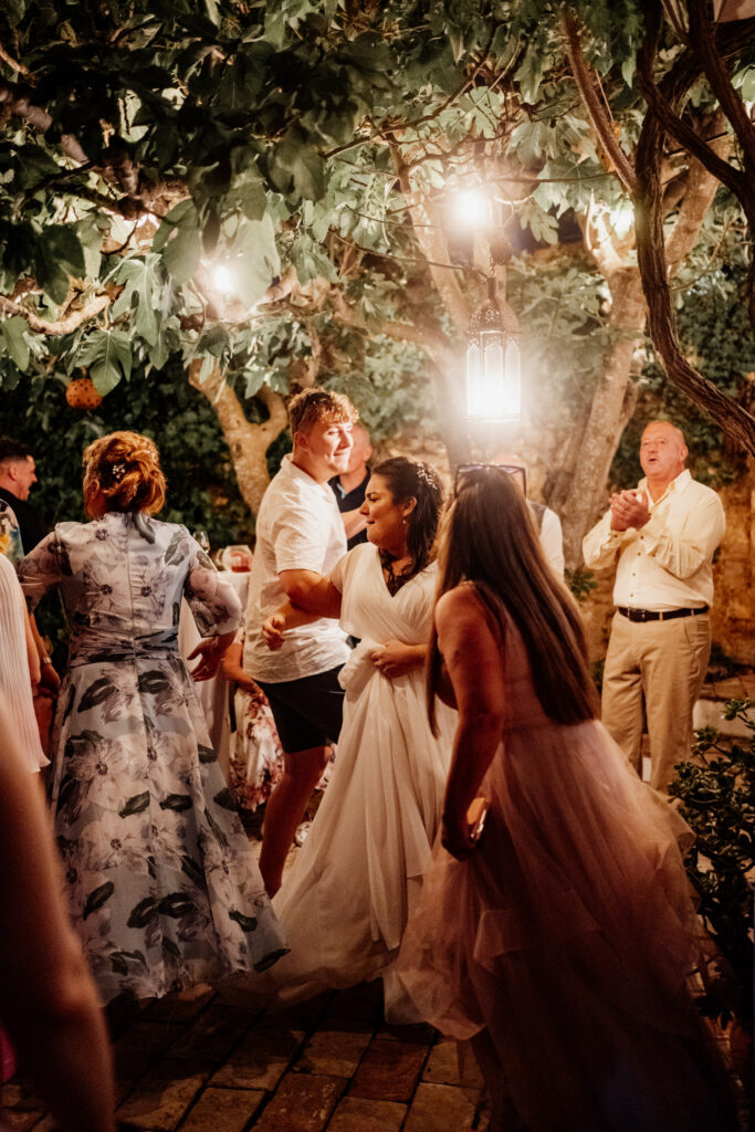 Wedding guests dancing beneath garden lights at night