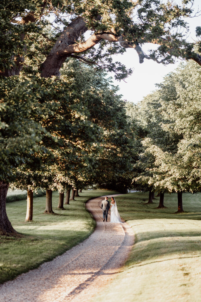 Newlyweds walking along a winding drive through the grounds