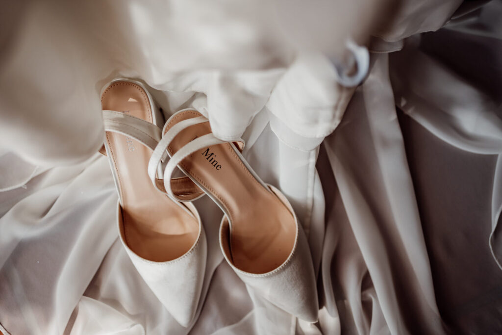 White bridal shoes resting on soft wedding dress fabric