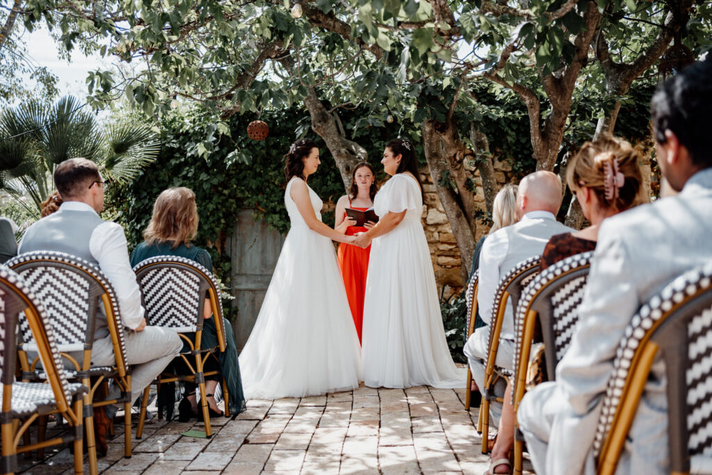 Two brides listening to their celebrant during an outdoor ceremony