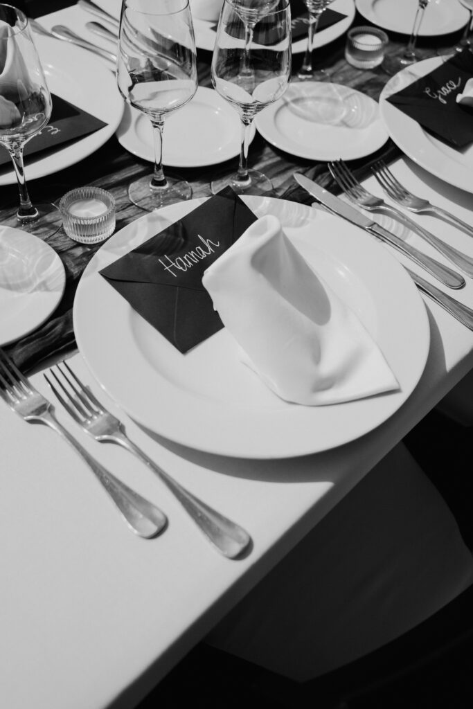 Black-and-white detail of folded napkins, menus and glasses on a reception table