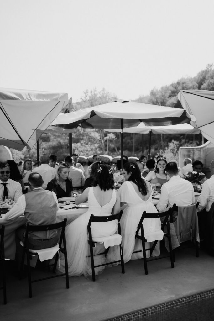 Black-and-white view of guests seated beneath reception parasols