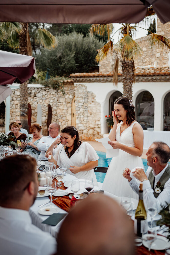 Bride smiling as she gives a speech beside the reception table