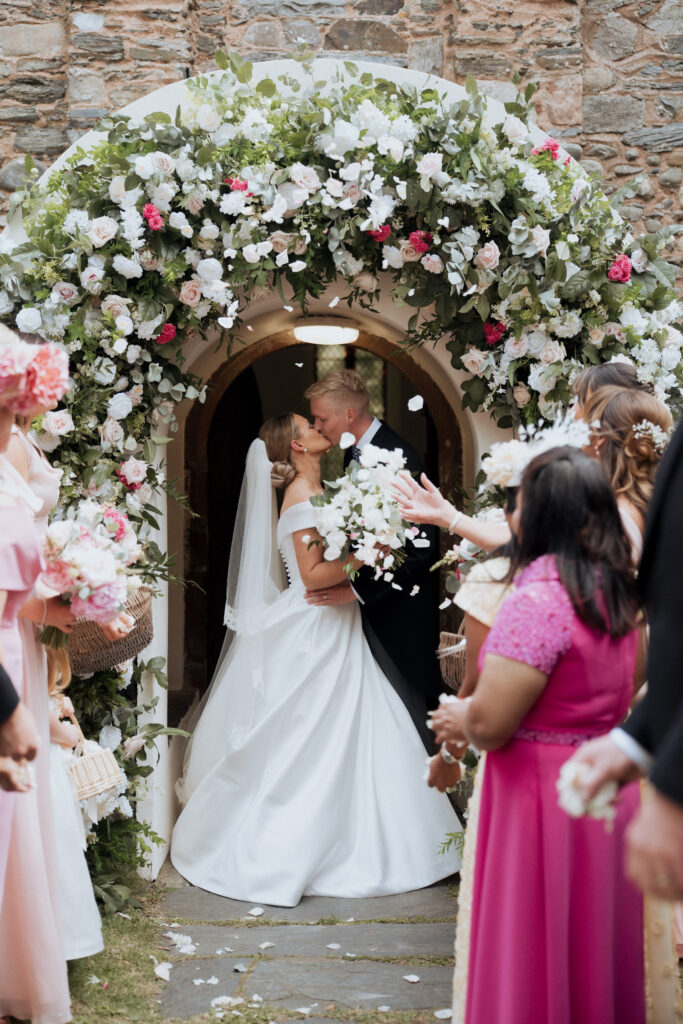 Couple kiss outside of Old Ballaugh Church following their wedding ceremony