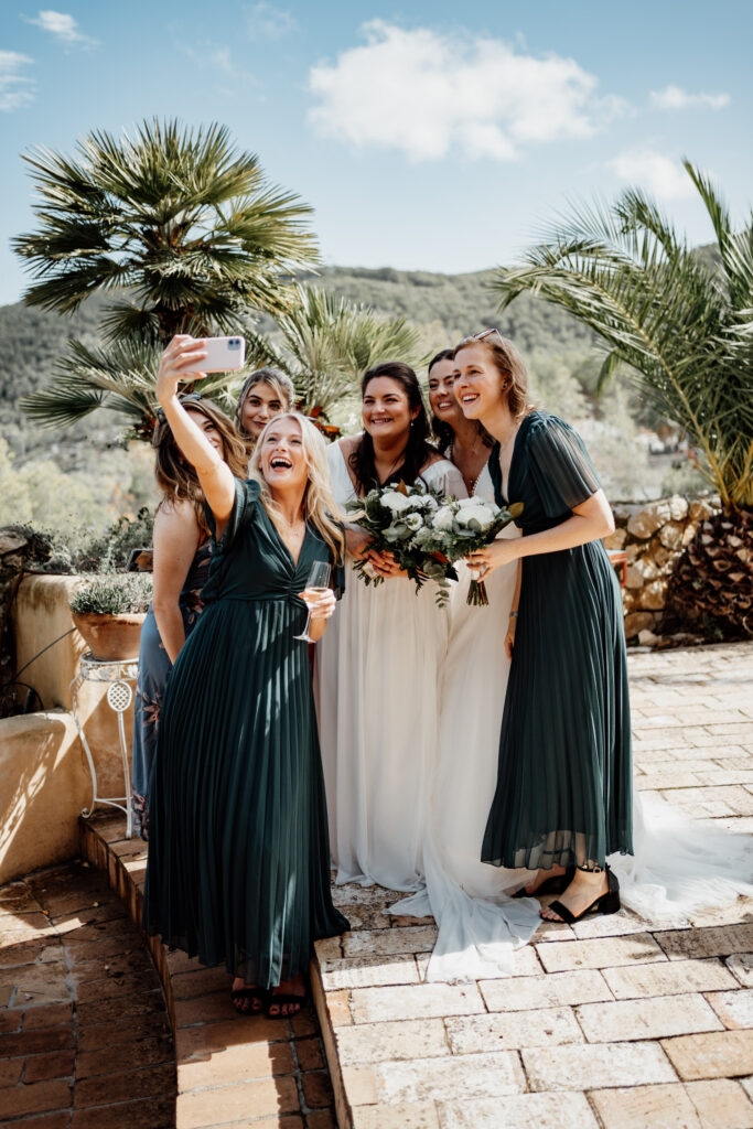 Bride posing with friends beside palm trees