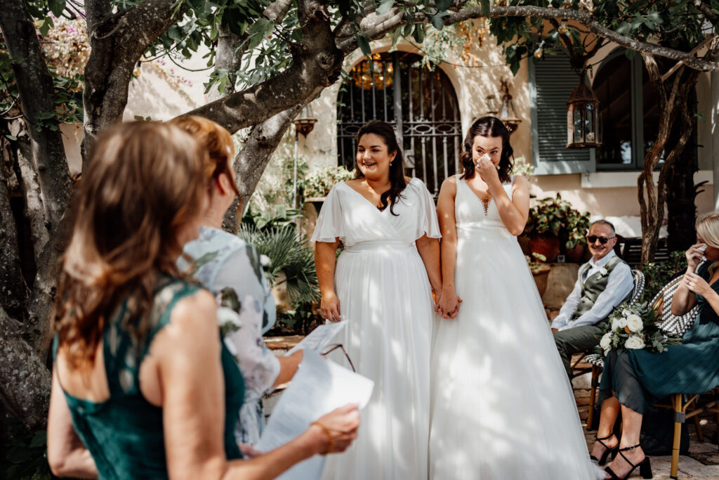 Two brides approaching the celebrant beneath the ceremony tree