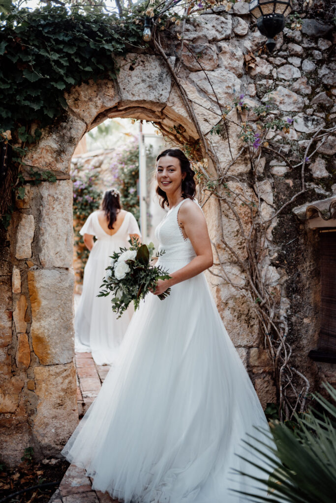 Bride holding a bouquet in a rustic stone archway