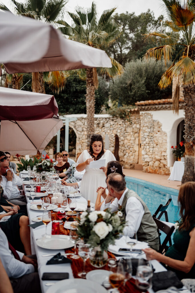 Bride giving a speech beside a long poolside table