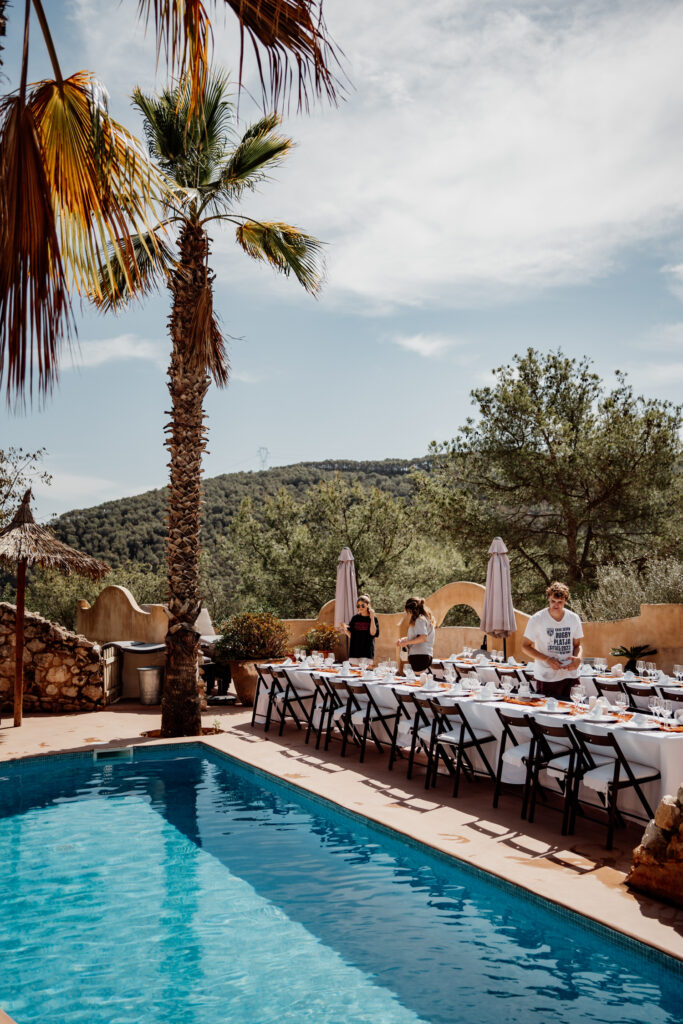 Poolside wedding tables set beneath parasols and palm trees
