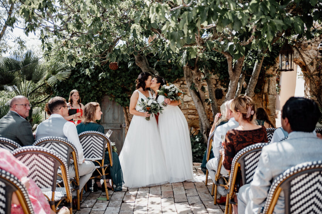 Outdoor wedding ceremony viewed between rows of seated guests