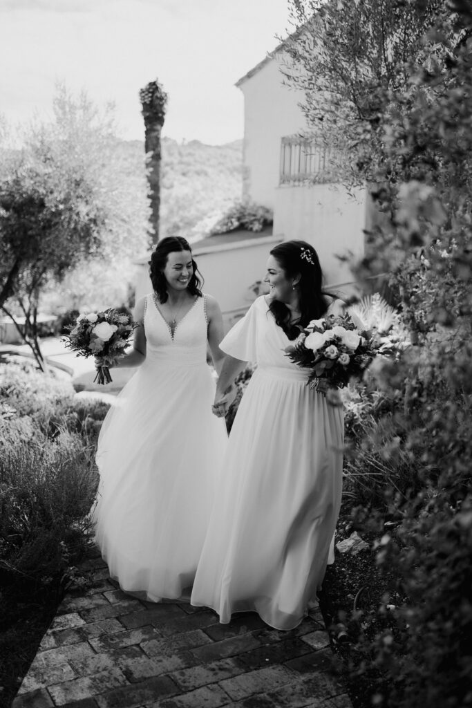 Black-and-white photograph of two brides walking with their bouquets