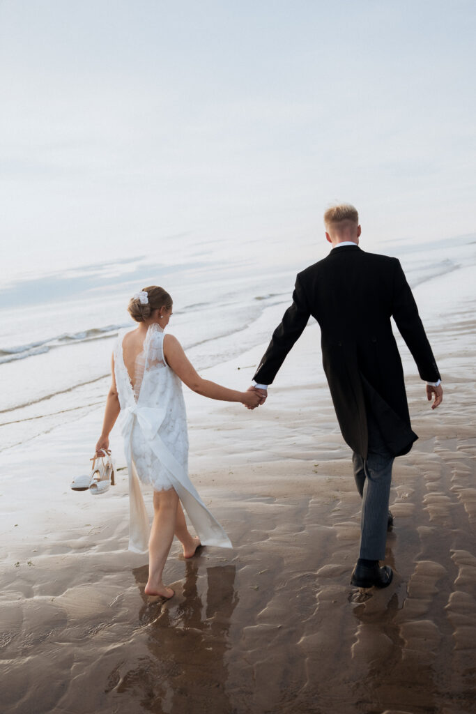 Couple holding hands while walking towards the sea