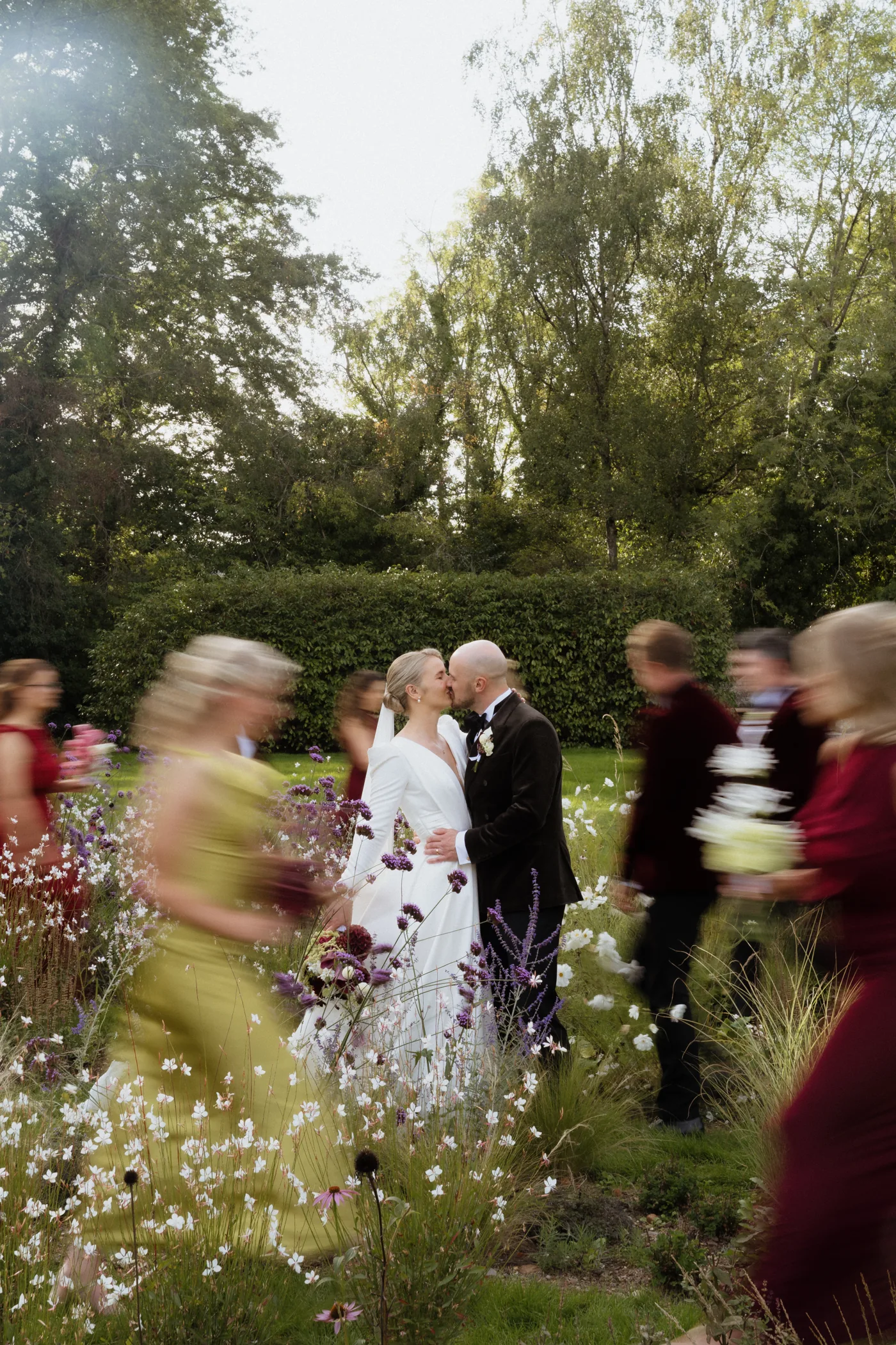 Couple kissing as their wedding guests move around them