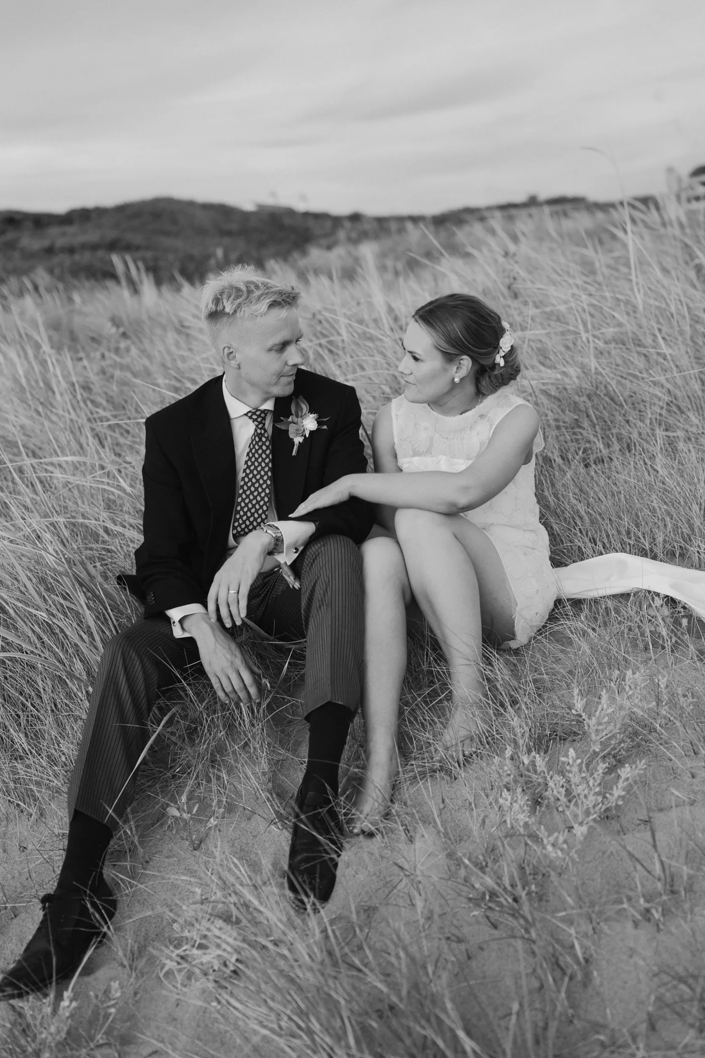 Black-and-white portrait of Natalie and Spencer sitting together among sand dunes