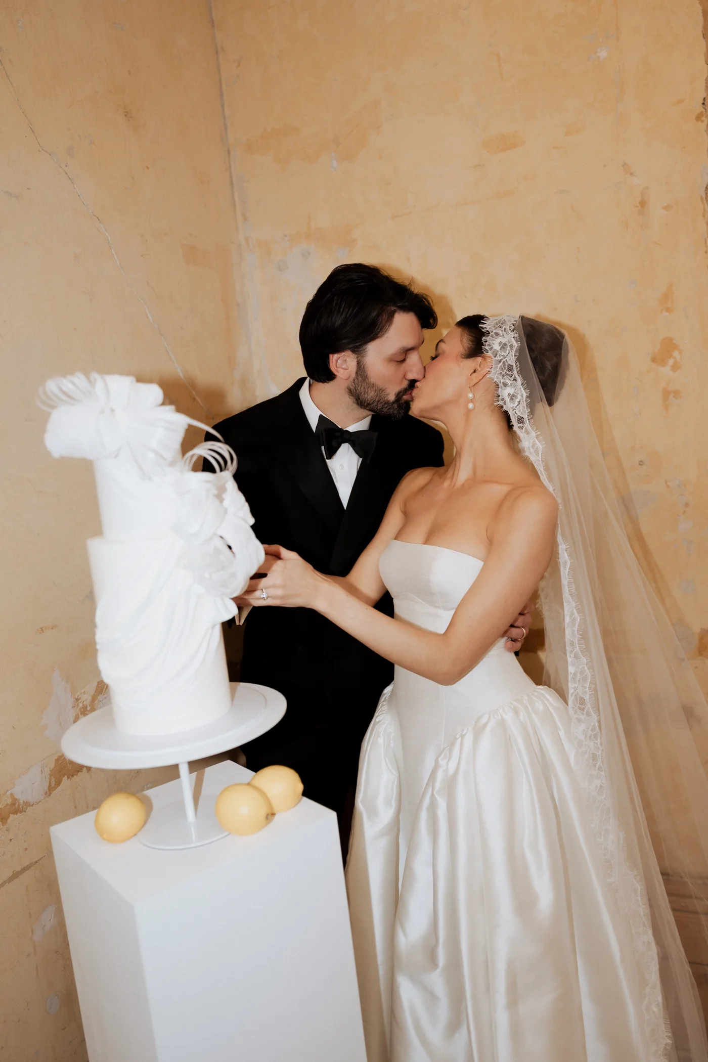 Couple kissing beside their wedding cake