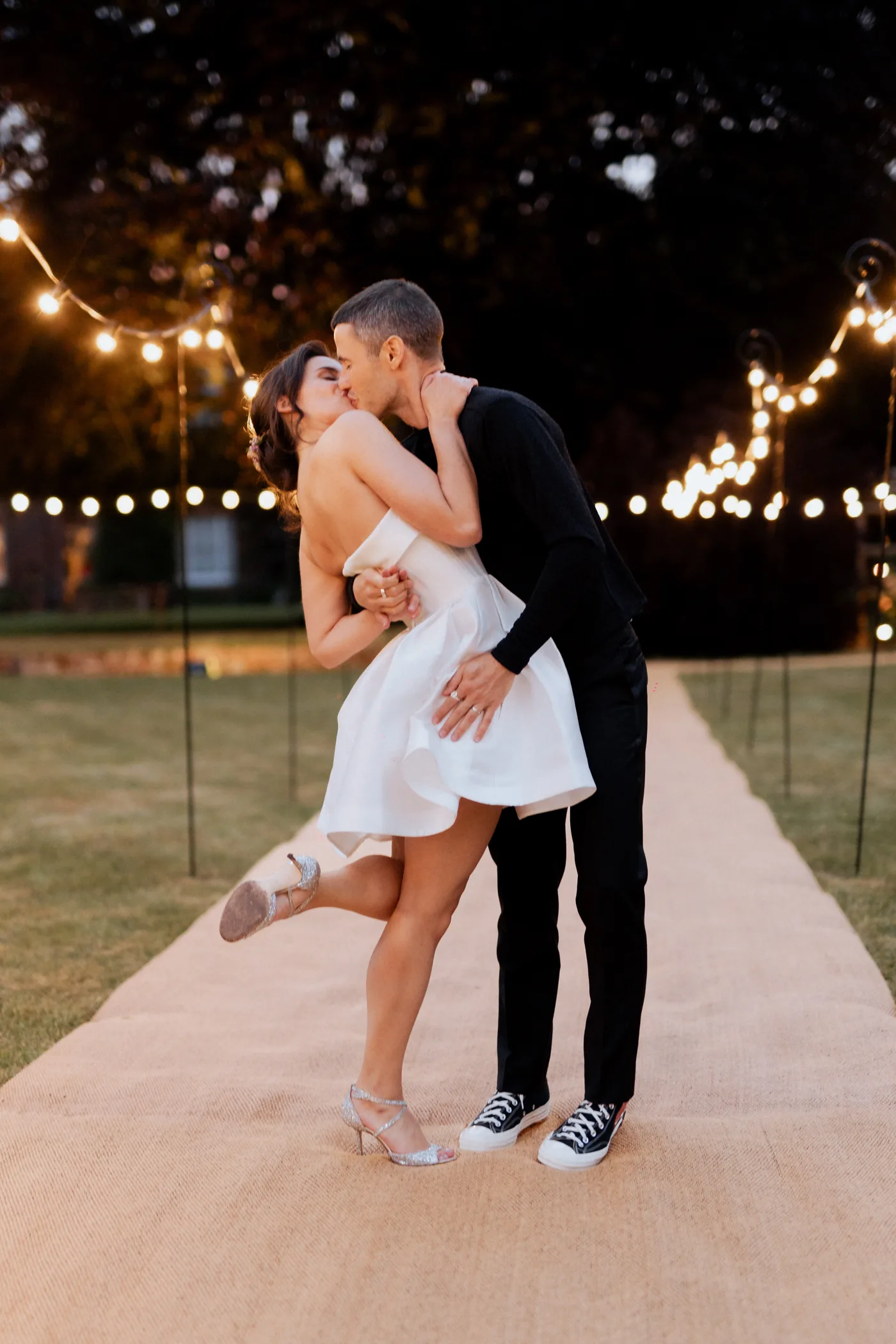 Couple kissing beneath evening festoon lights