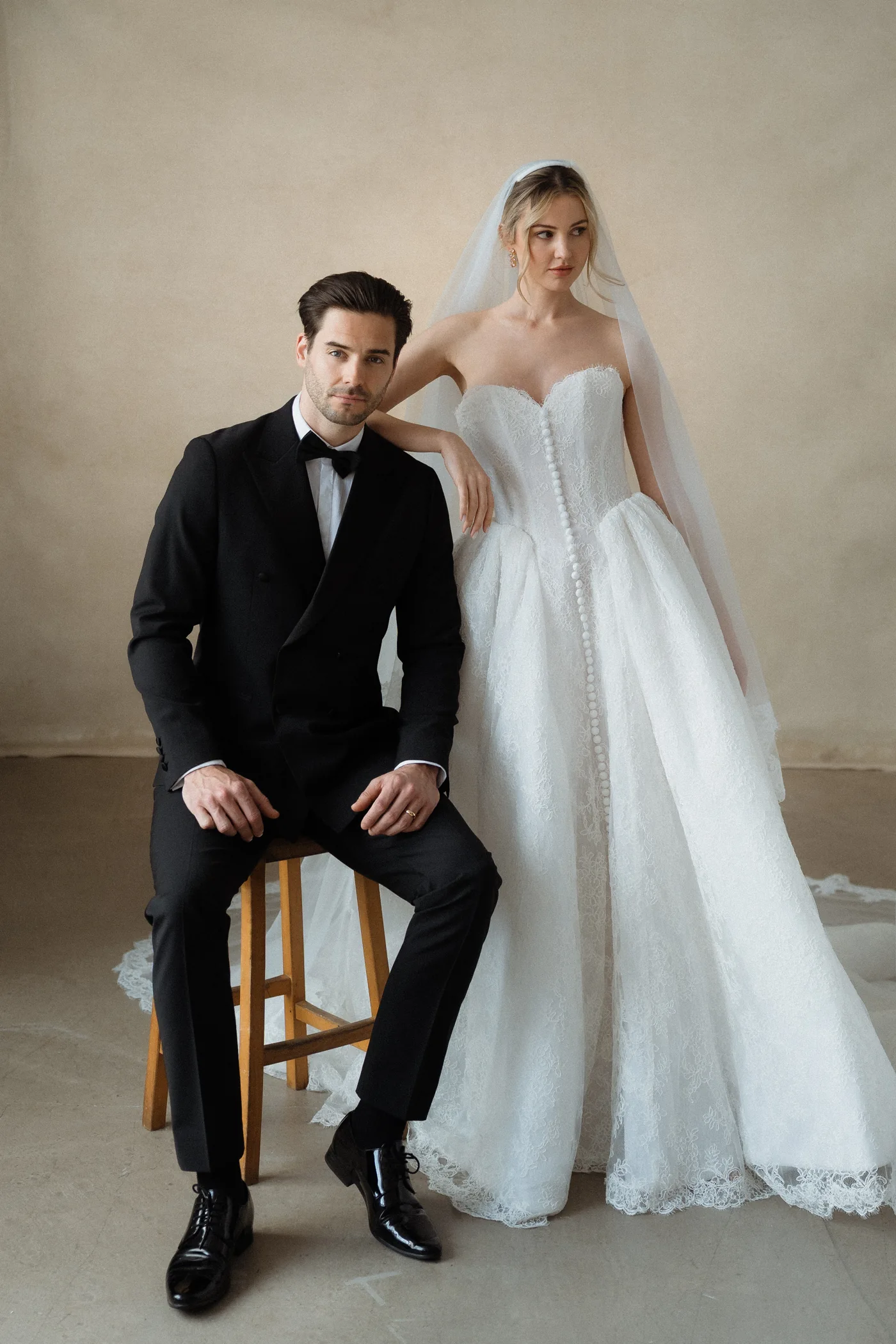 Editorial portrait of a seated groom and standing bride