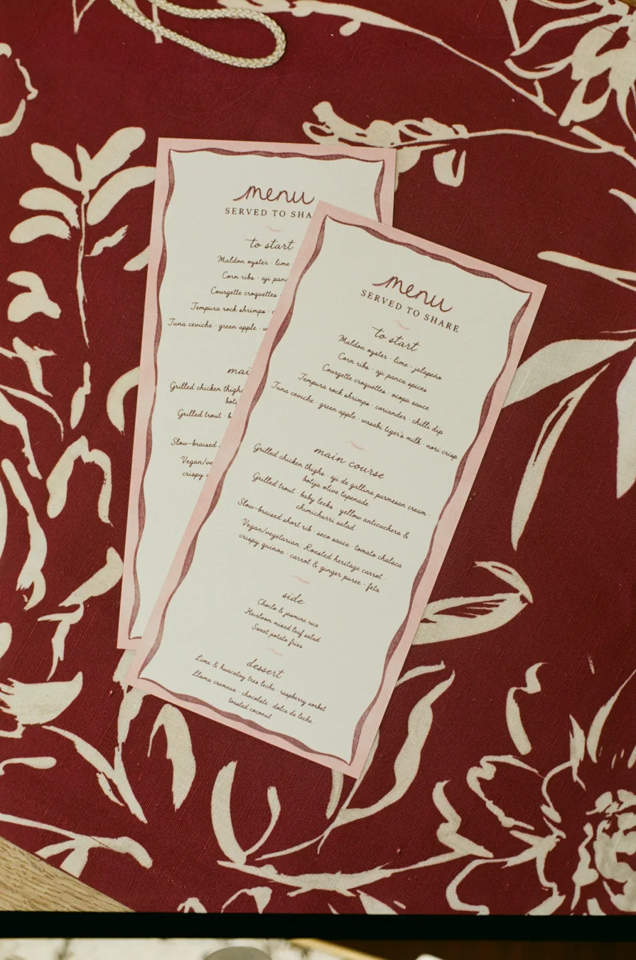35mm film photograph of wedding menus on burgundy floral linen