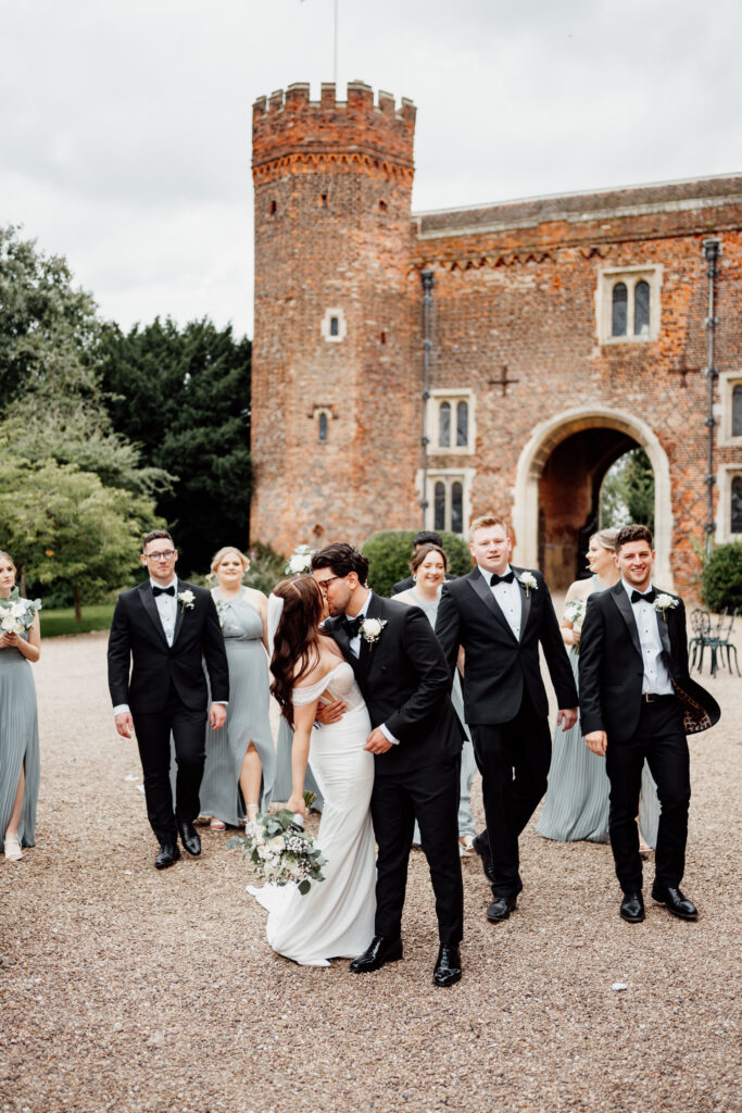 Bride and groom kiss in front of wedding party