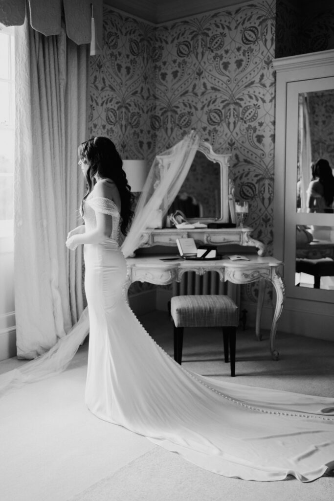 Bride in dress looking out of window in bridal suite of Hodsock Priory