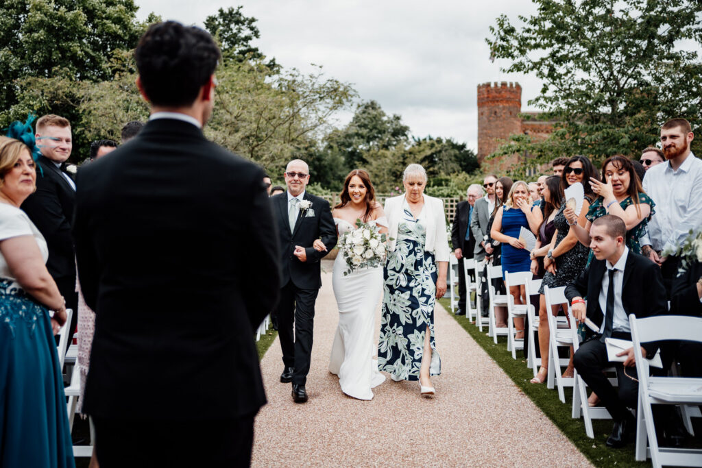 Bride walking down aisle with father and mother